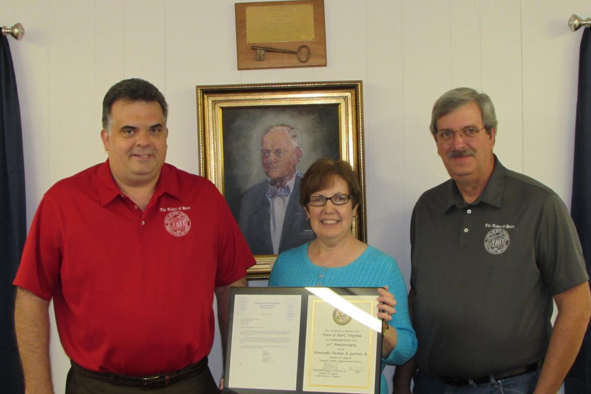 With a portrait of our town’s namesake, Mr. John L. Hurt, Jr., hanging statuesque behind them, Mrs. Poindexter presents Mayor Ga